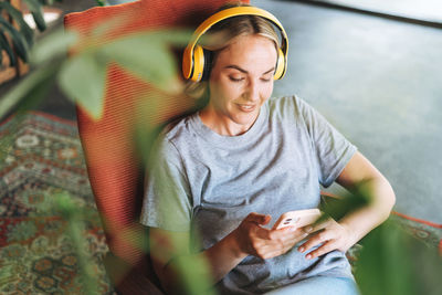 Smiling young woman using mobile phone while sitting outdoors