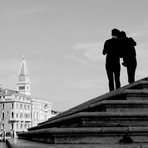 Rear view of couple standing on steps by st mark cathedral against sky