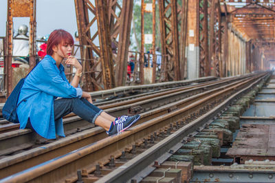 Portrait of girl sitting on railroad tracks