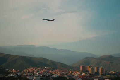 Airplane flying over cityscape against sky