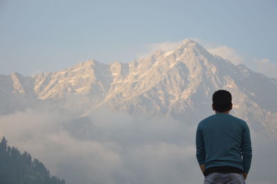 Man standing against mountains during foggy weather