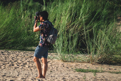 Side view of man photographing against grass