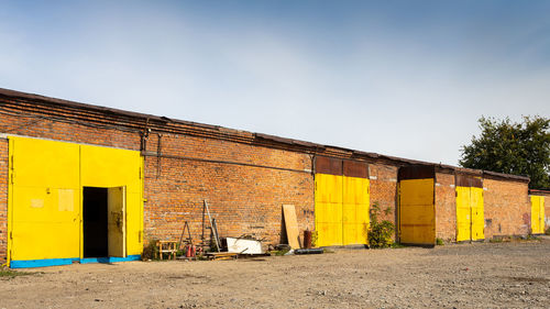 Facade of a yellow metal warehouse, a commercial building with entrances for cars for storing goods. 