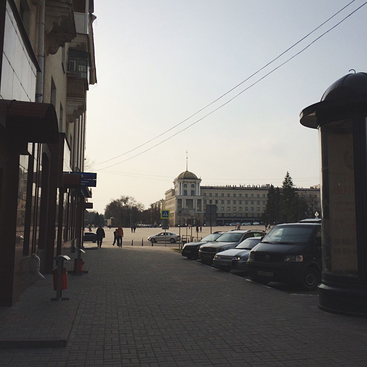 building exterior, architecture, built structure, street, clear sky, transportation, the way forward, city, power line, street light, sky, road, mode of transport, car, cable, city life, residential structure, residential building, electricity pylon, incidental people