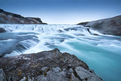 Scenic view of waterfall against sky