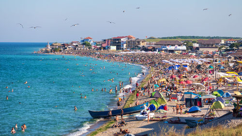 Crowd enjoying at beach against clear sky