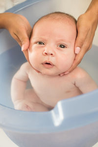 Cropped hands of mother bathing son in bathtub at bathroom