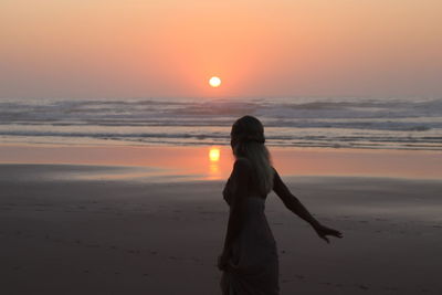 Woman standing at beach during sunset