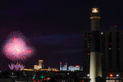 Firework display over illuminated buildings in city at night