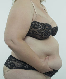 Close-up of shirtless young woman over white background