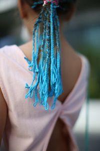 Rear view of girl with blue wool braided in hair outdoors