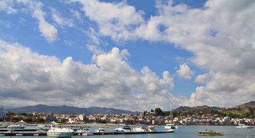 Sailboats moored in harbor against sky