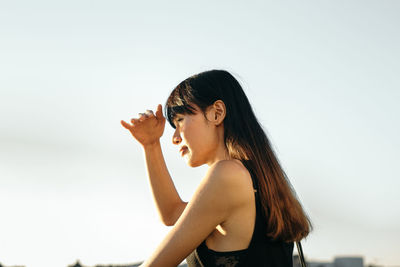 Young woman standing against clear sky