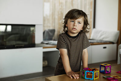 Contemplative boy with toy block on table at home