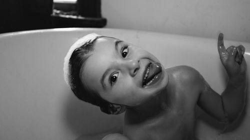 Portrait of boy sticking out tongue while sitting in bathtub