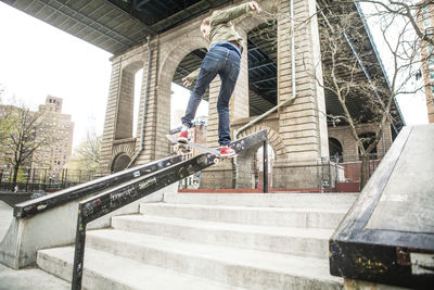 Man skateboarding on railing at steps