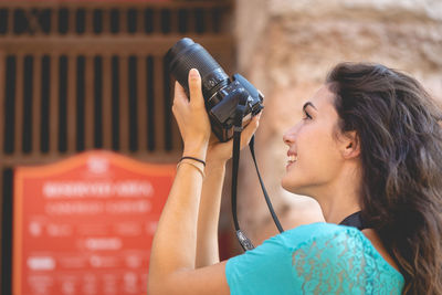 Smiling young woman photographing in city