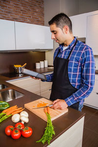 Young man preparing food in kitchen at home
