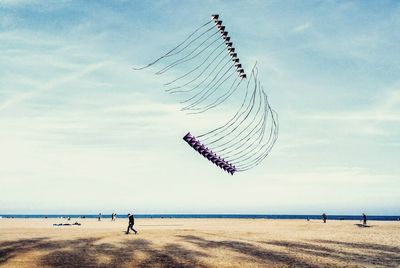 Wind turbines on beach against sky