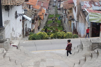 Rear view of woman walking on footpath amidst buildings in city