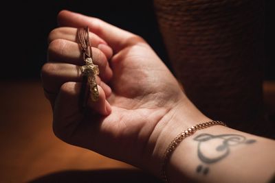 Close-up of human hand holding cross necklace