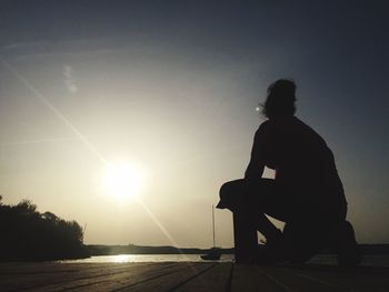 Rear view of silhouette man sitting on seat against sky