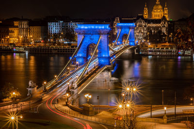 Illuminated suspension bridge over river at night