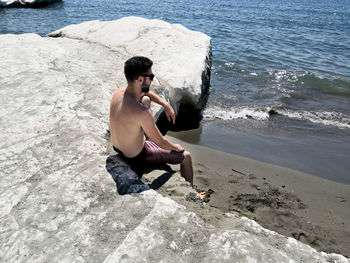 High angle view of shirtless man sitting on beach