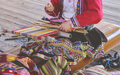 Indigenous woman showing traditional weaving technique and textile making in the andes mountain 