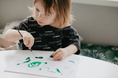 The boy draws with pencils at the kitchen, closeup. high quality photo