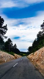 Empty road amidst trees against sky