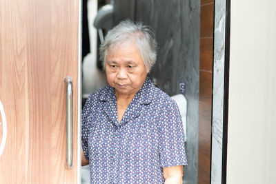 Portrait of woman standing against door at home