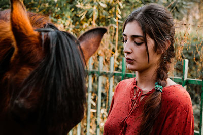 Close-up of young woman standing with horse outdoors