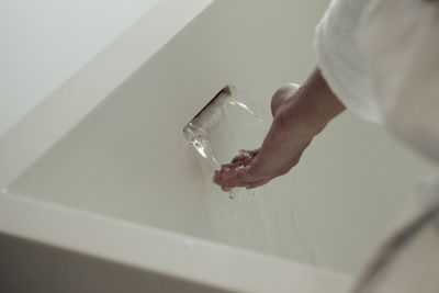 Close-up of hand touching water at bathtub