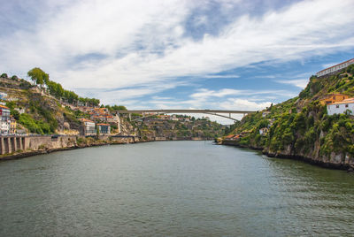 Bridge over sea by buildings in town against sky