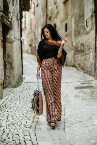 Full length portrait of woman standing against brick wall