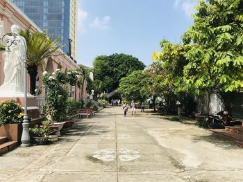 Street amidst trees and buildings against sky