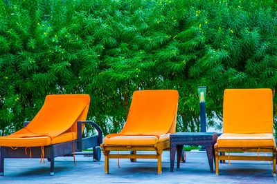 Empty chairs on beach against clear orange sky