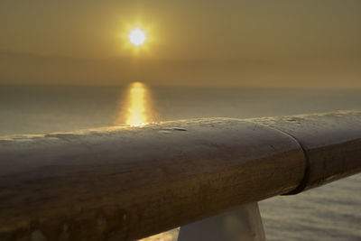 Close-up of railing against sea during sunset