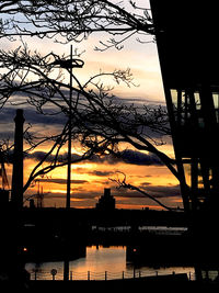 Silhouette of bridge over river during sunset