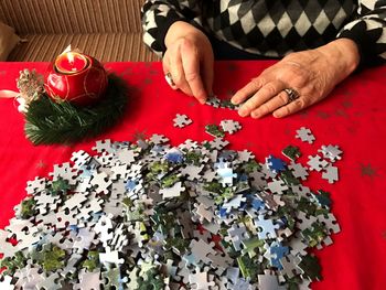 Midsection of woman assembling jigsaw puzzle pieces on table