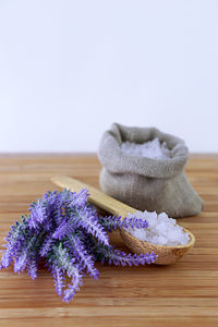 Bath salt and purple flowers on table
