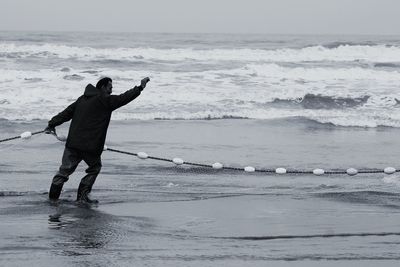 Rear view of man on beach against sky