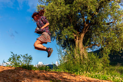 Low angle view of person jumping against trees