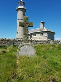 Tombstones at grassy cemetery against lighthouse