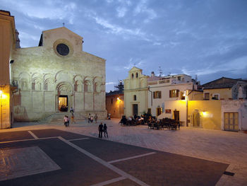 People walking in illuminated temple against sky