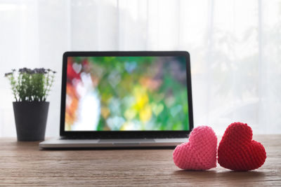 Close-up of heart shape wool and laptop on table