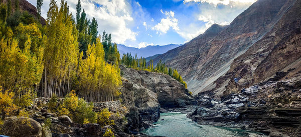 Panoramic view of stream amidst mountains against sky