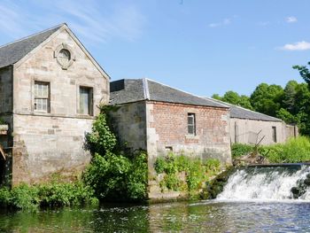 View of sawmill by river against sky