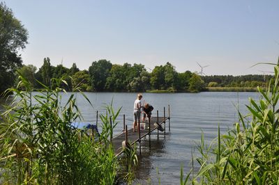 People in lake against clear sky